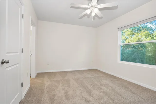 an empty room with a window and a fan