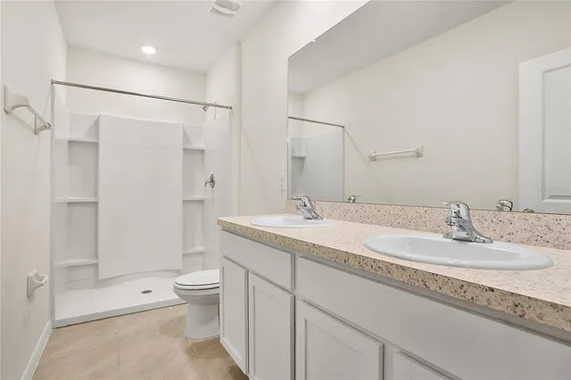a bathroom with a double vanity sink toilet and shower