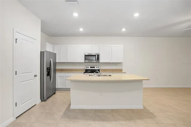 a view of kitchen with kitchen island a sink a stove and refrigerator