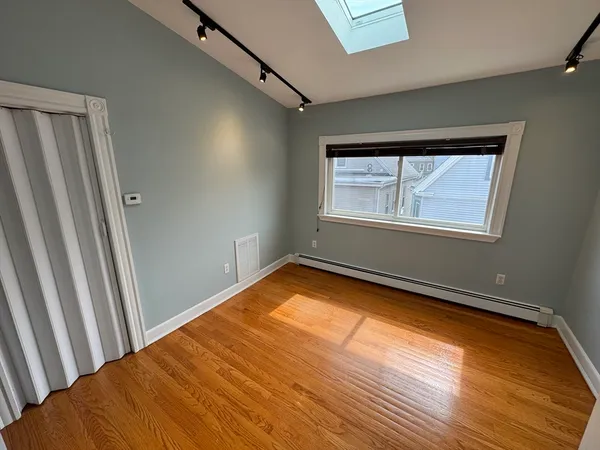 a view of an empty room with wooden floor and cabinet