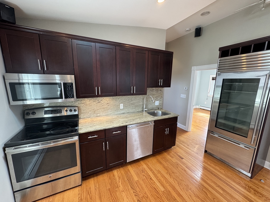 24 Ellington Road, Unit 3 Somerville, MA 02144 - Photo 3 of 21 a kitchen with stainless steel appliances wooden cabinets and a stove top oven