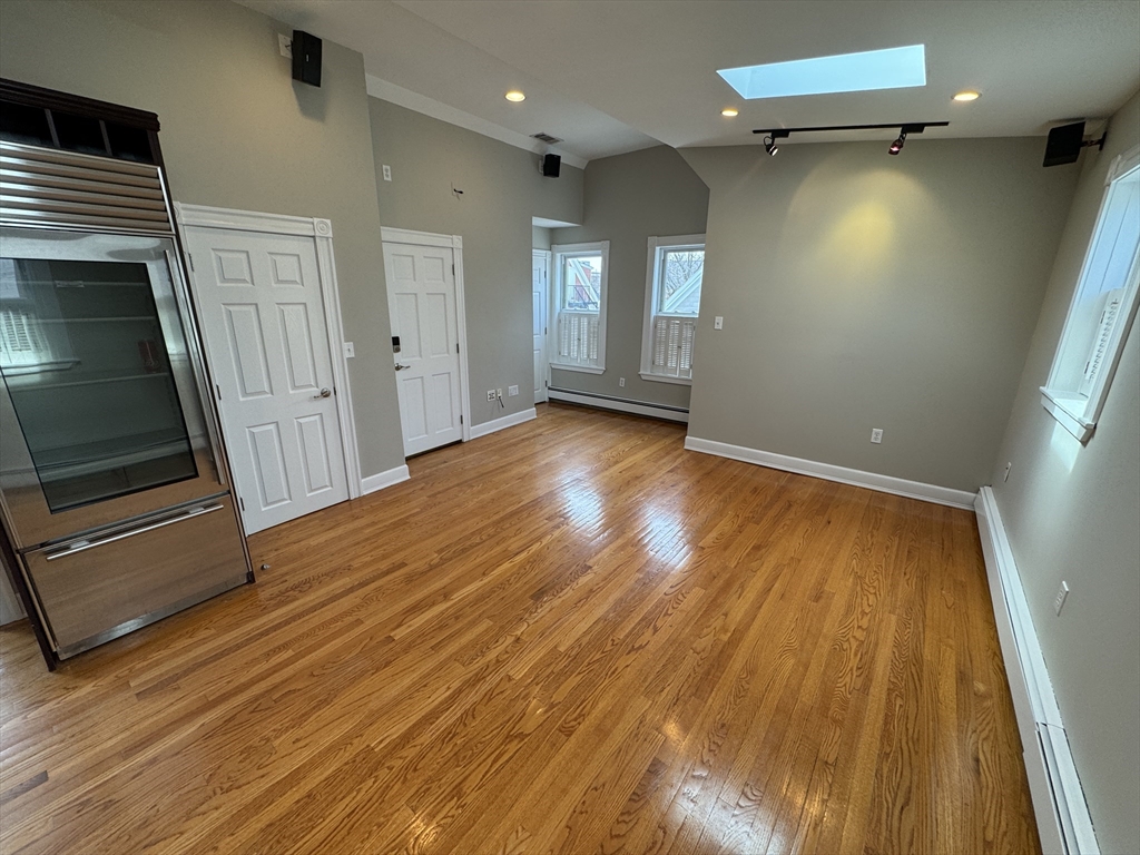 24 Ellington Road, Unit 3 Somerville, MA 02144 - Photo 5 of 21 a view of an empty room with wooden floor and a window