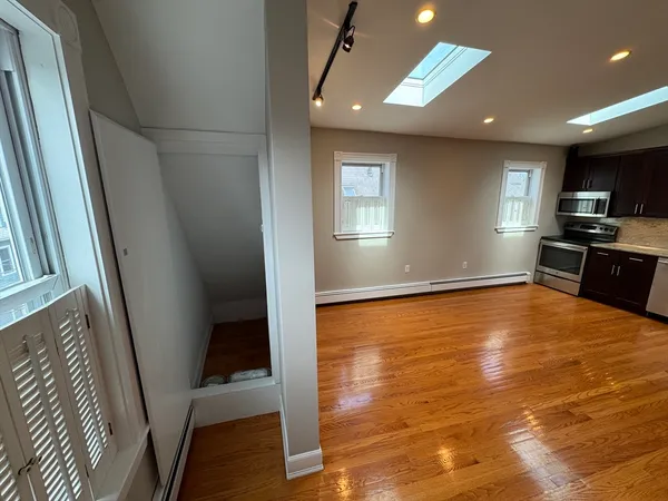 a view of empty room with wooden floor and fan