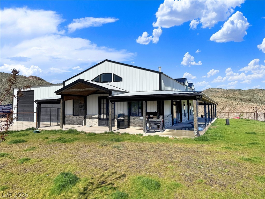 9393 North 93rd Highway Caliente, NV 89008 - Photo 9 of 41 Perched on a hill, this expansive residence combines classic stone with modern metal siding under an open sky.
