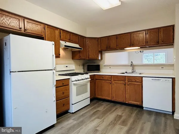 a kitchen with granite countertop a refrigerator stove top oven and sink