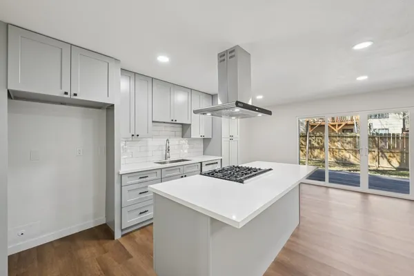 a kitchen that has a sink a stove and wooden floor