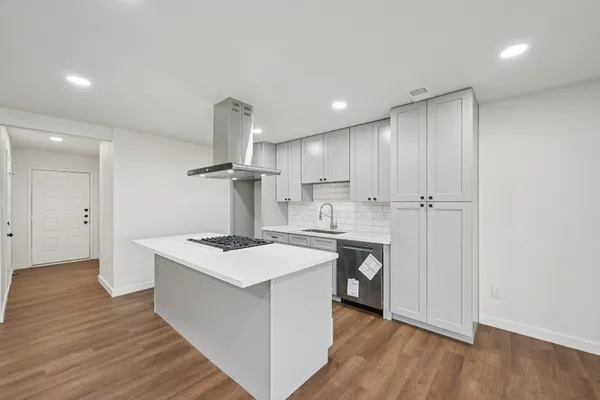 a kitchen that has a lot of cabinets in it and wooden floors