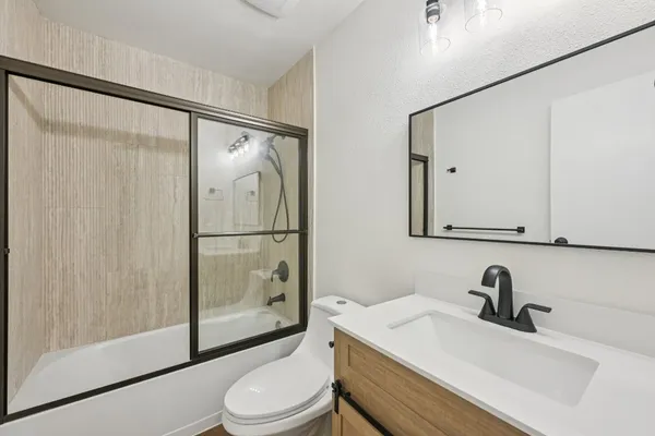 an empty room with wooden floor ceiling fan and windows
