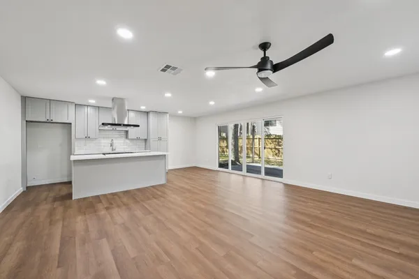 a view of an empty room with wooden floor and a fireplace