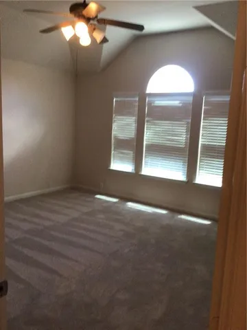 an empty room with a chandelier fan and windows