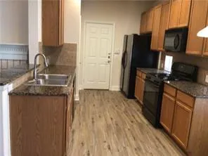 a kitchen with granite countertop a refrigerator stove and sink