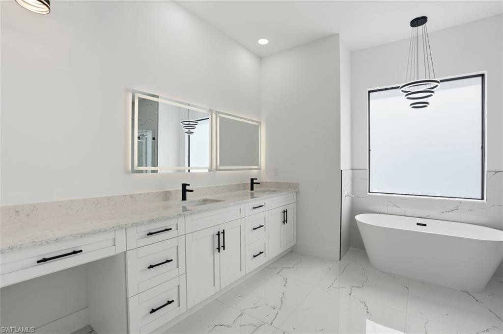 2930 20th Street Southwest Lehigh Acres, FL 33976 - Photo 33 of 43 a bathroom with a granite countertop sink mirror and a bathtub