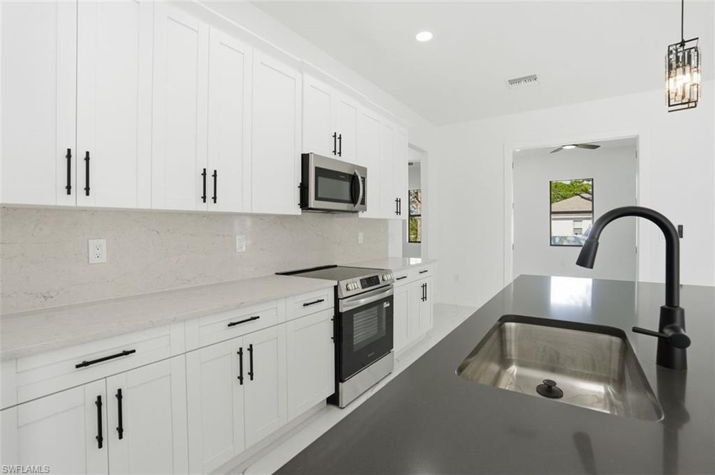 2930 20th Street Southwest Lehigh Acres, FL 33976 - Photo 4 of 43 a kitchen with white cabinets and stainless steel appliances