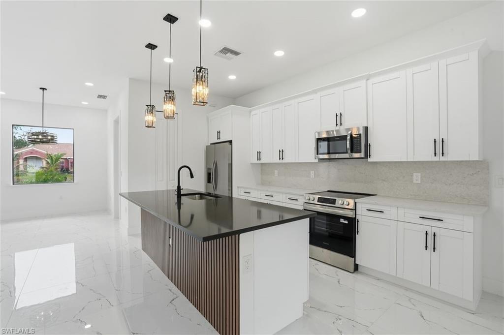2930 20th Street Southwest Lehigh Acres, FL 33976 - Photo 9 of 43 a kitchen with stainless steel appliances granite countertop a sink a stove and a refrigerator