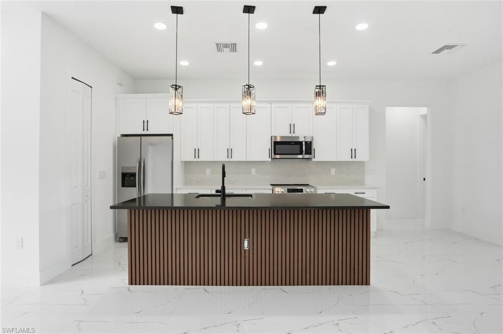 2930 20th Street Southwest Lehigh Acres, FL 33976 - Photo 10 of 43 a kitchen with stainless steel appliances granite countertop a sink a stove and a refrigerator