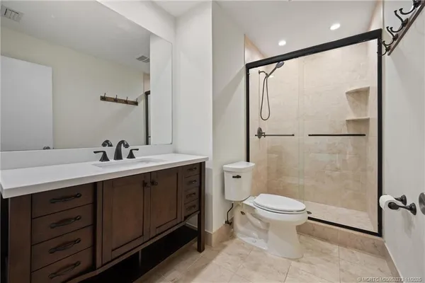 a bathroom with a double vanity sink toilet mirror and shower
