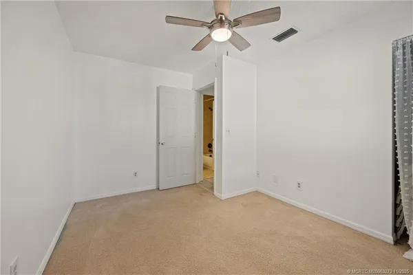 an empty room with closet and a chandelier fan