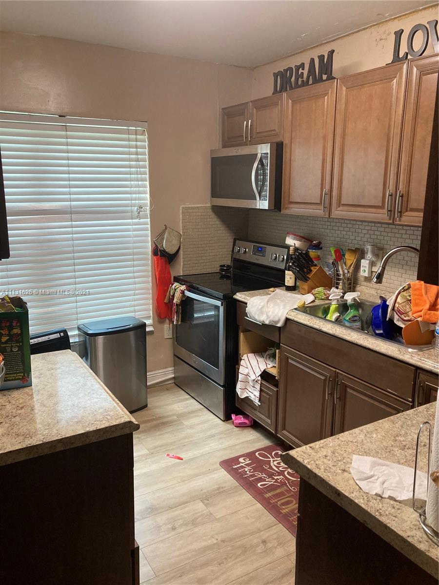 4172 Inverrary Drive, Unit 112 Lauderhill, FL 33319 - Photo 16 of 18 a kitchen with stainless steel appliances kitchen island granite countertop a refrigerator a stove a sink dishwasher and wooden cabinets