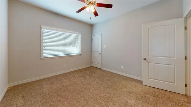 an empty room with a ceiling fan and carpet