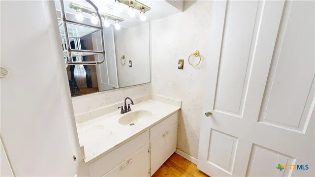 a bathroom with a sink and mirror with bathtub
