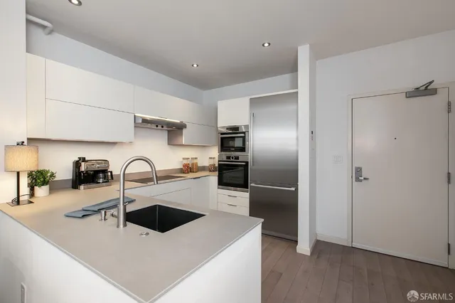 a kitchen with stainless steel appliances a sink a stove and a refrigerator with wooden floor