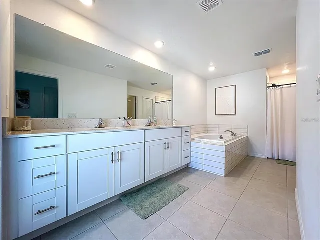 a large bathroom with a double vanity sink a mirror and a bathtub
