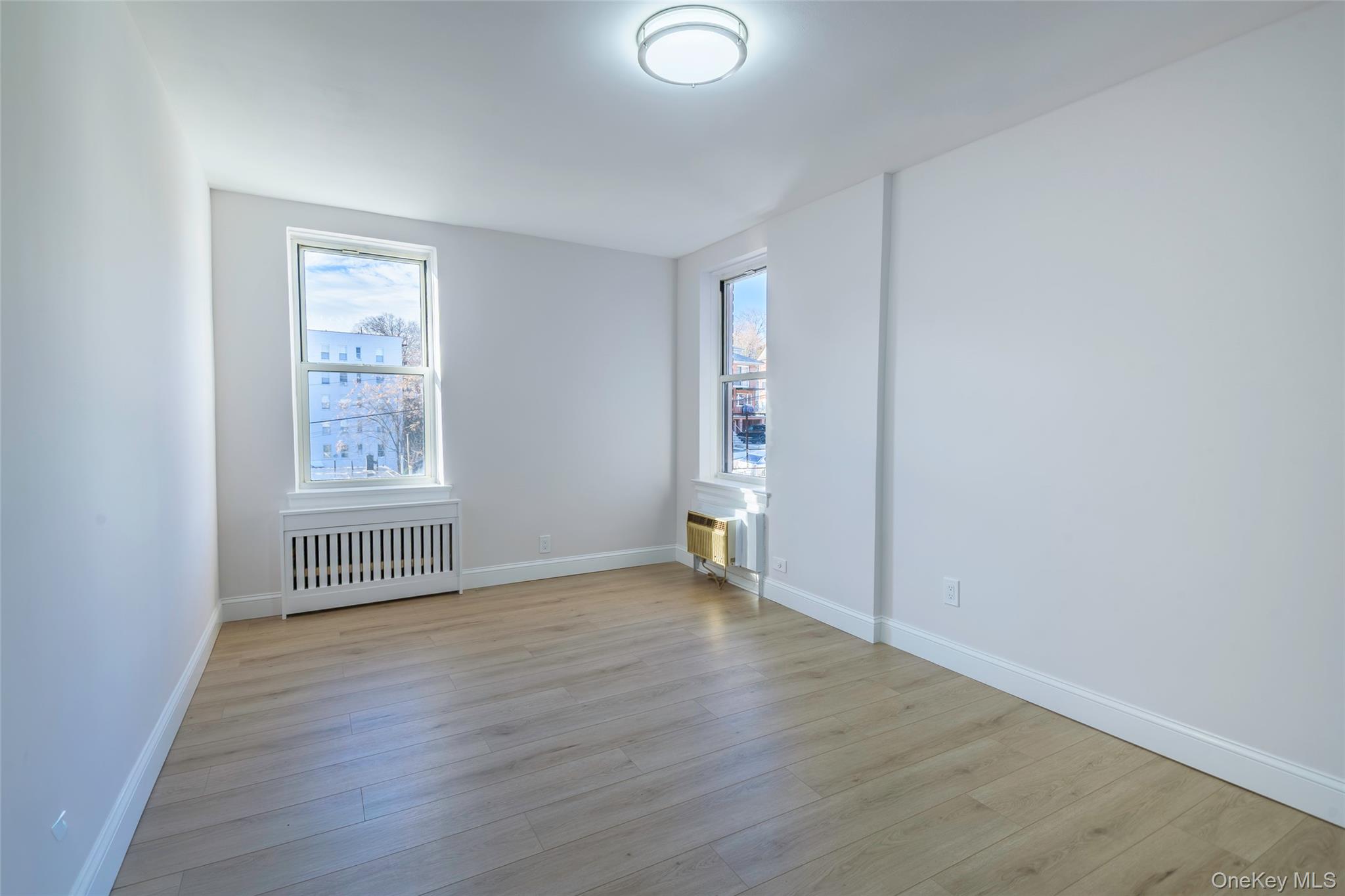 125 Bronx River Road, Unit 2E Yonkers, NY 10704 - Photo 19 of 31 an empty room with wooden floor and windows