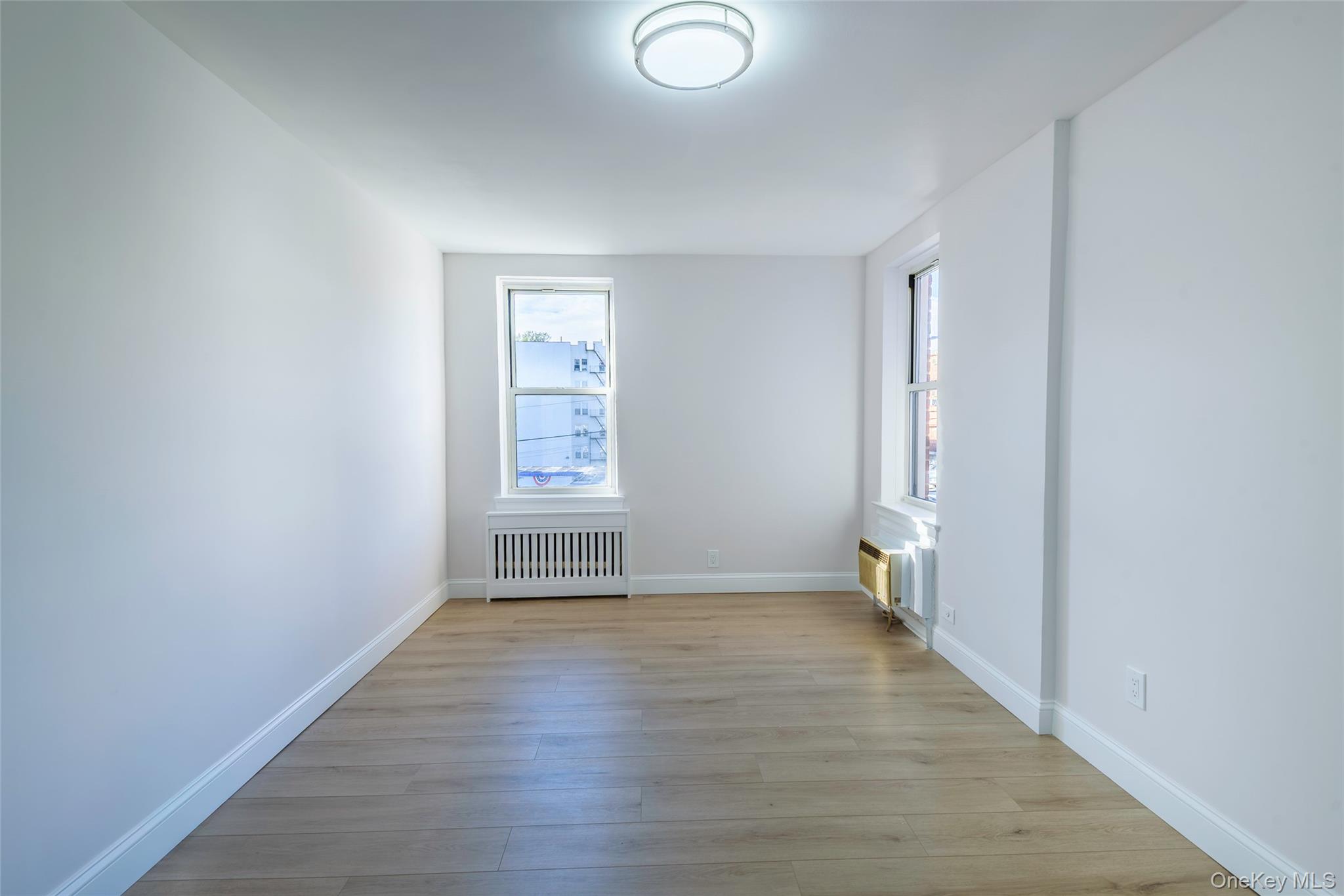 125 Bronx River Road, Unit 2E Yonkers, NY 10704 - Photo 20 of 31 an empty room with wooden floor and windows