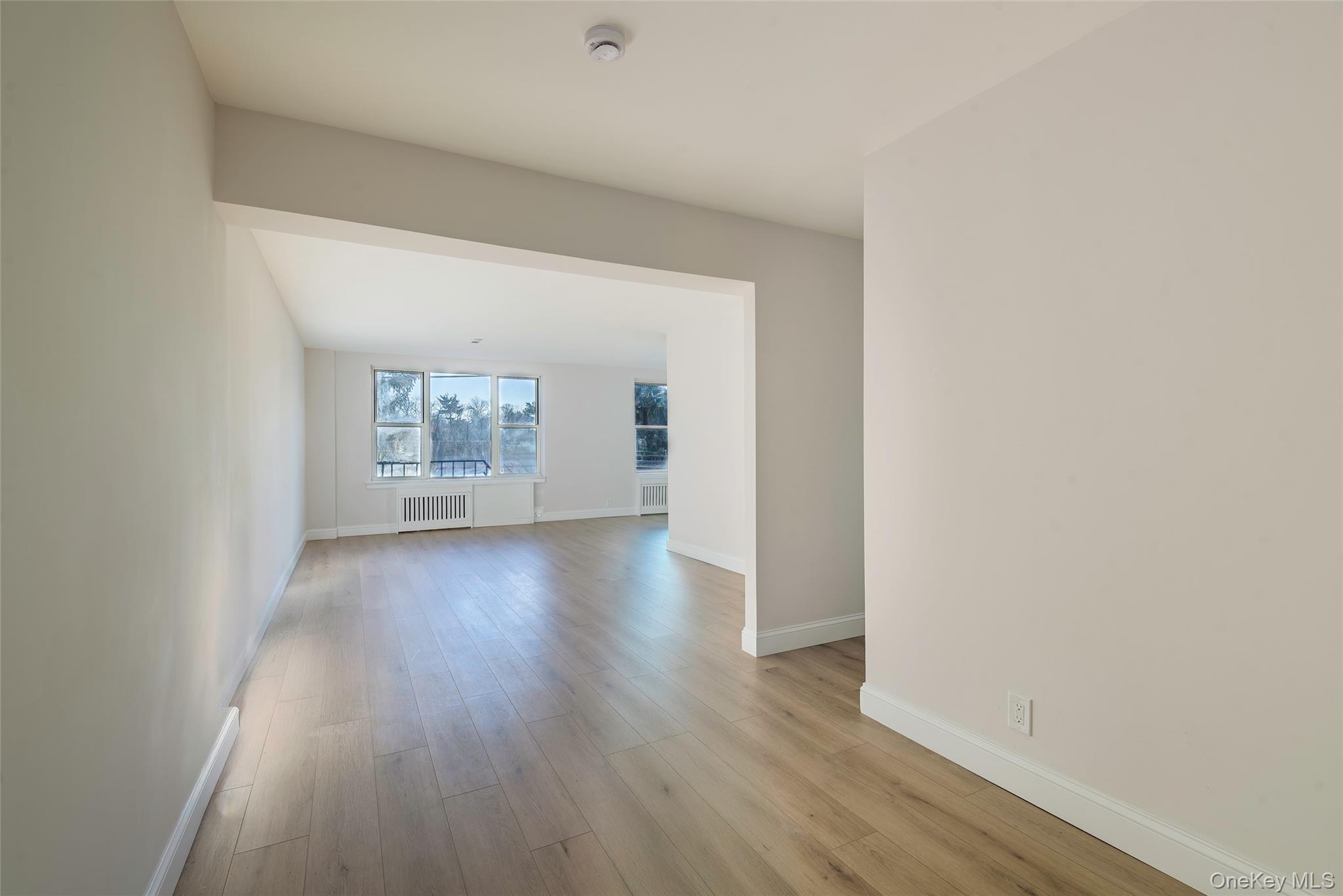125 Bronx River Road, Unit 2E Yonkers, NY 10704 - Photo 2 of 31 an empty room with wooden floor and windows