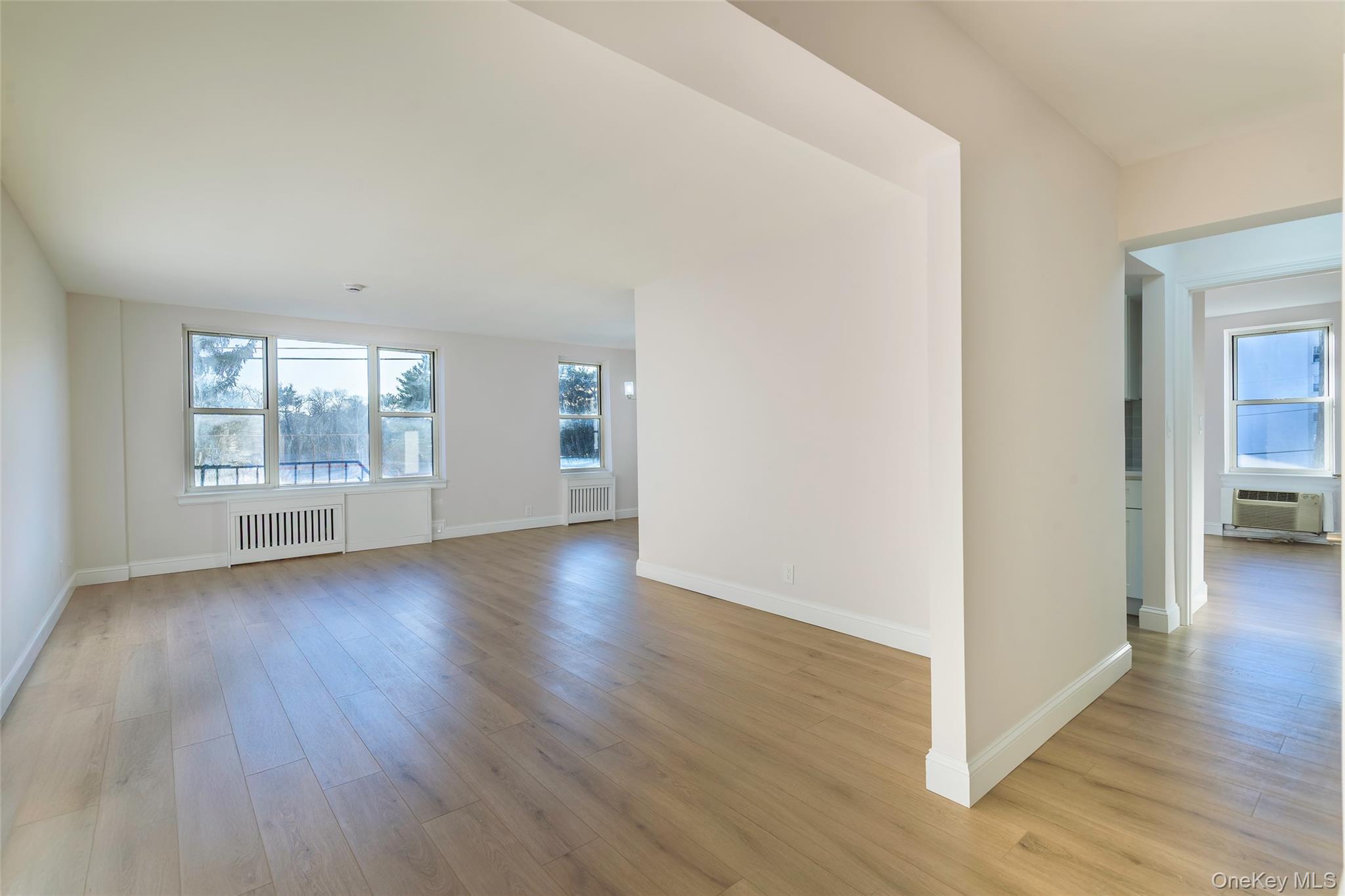125 Bronx River Road, Unit 2E Yonkers, NY 10704 - Photo 4 of 31 an empty room with wooden floor and windows