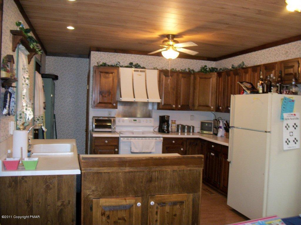 581 Wren Lane Bushkill, PA 18324 - Photo 2 of 16 a kitchen with kitchen island a stove a refrigerator and a dining table with wooden floor