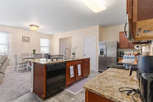 a kitchen with stainless steel appliances granite countertop a stove top oven a sink dishwasher a dining table and chairs with wooden floor