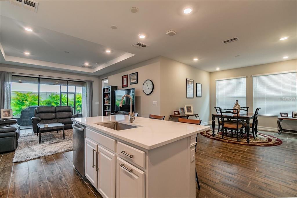 4738 Tramanto Lane Wesley Chapel, FL 33543 - Photo 12 of 45 a large kitchen with kitchen island a large island a stove a table and chairs in it