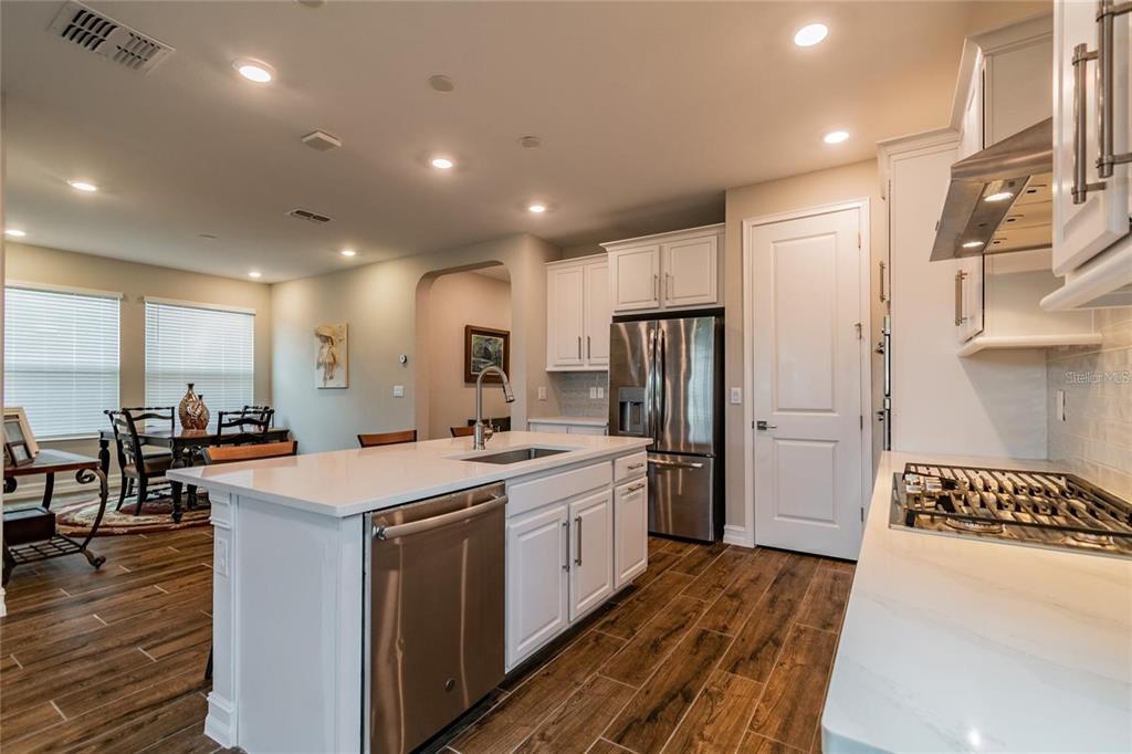4738 Tramanto Lane Wesley Chapel, FL 33543 - Photo 13 of 45 a kitchen with stainless steel appliances a stove a sink a refrigerator white cabinets and wooden floor