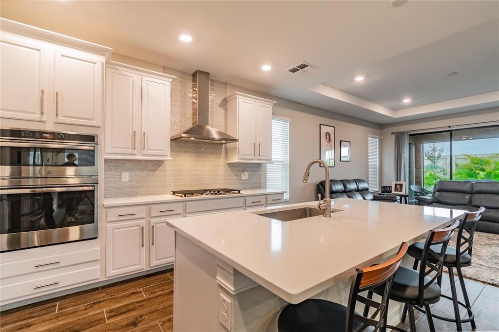 4738 Tramanto Lane Wesley Chapel, FL 33543 - Photo 10 of 45 a kitchen with stainless steel appliances granite countertop a stove top oven a sink a dining table and chairs with wooden floor