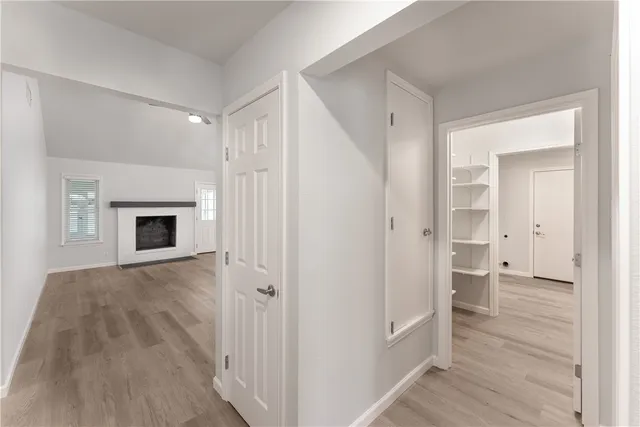 a view of an empty room with wooden floor and a fireplace
