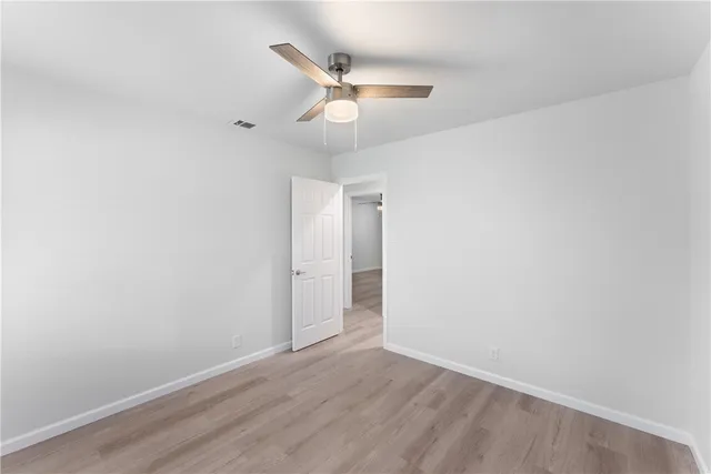an empty room with a window and ceiling fan