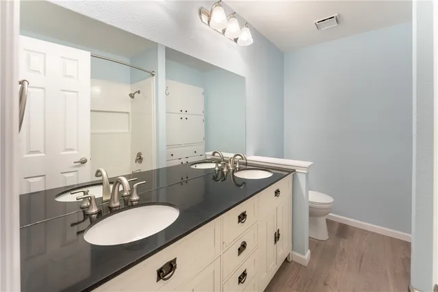 a bathroom with a granite countertop sink a toilet and a mirror