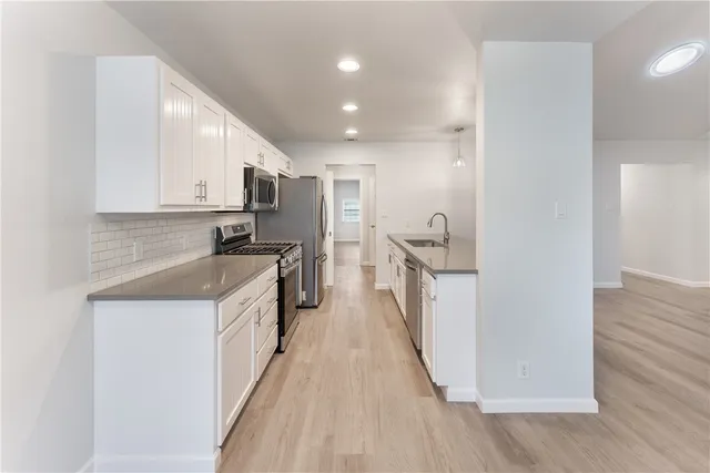 a kitchen with a sink a counter top space stainless steel appliances and cabinets