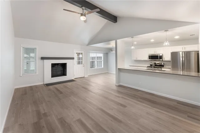 a view of kitchen and empty room with wooden floor