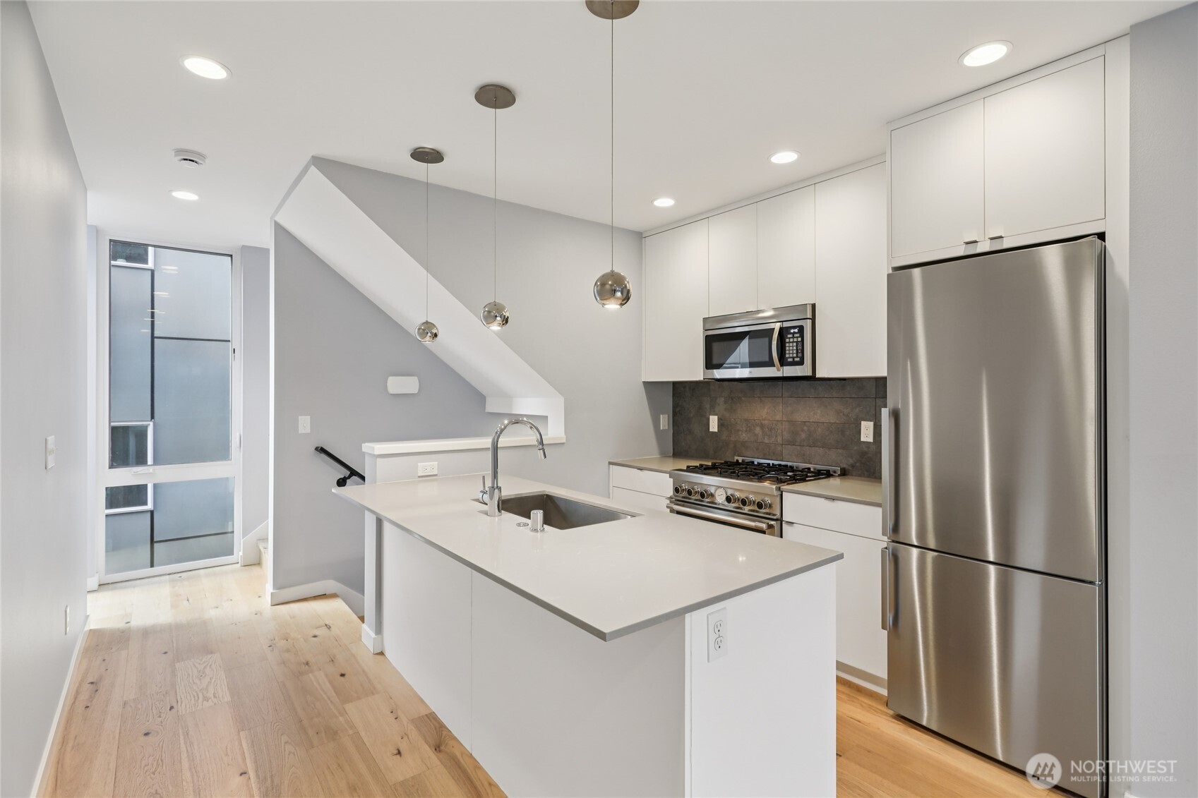 1117 Northwest 56th Street, Unit D Seattle, WA 98107 - Photo 5 of 32 a kitchen that has a refrigerator a stove and a sink with wooden floor
