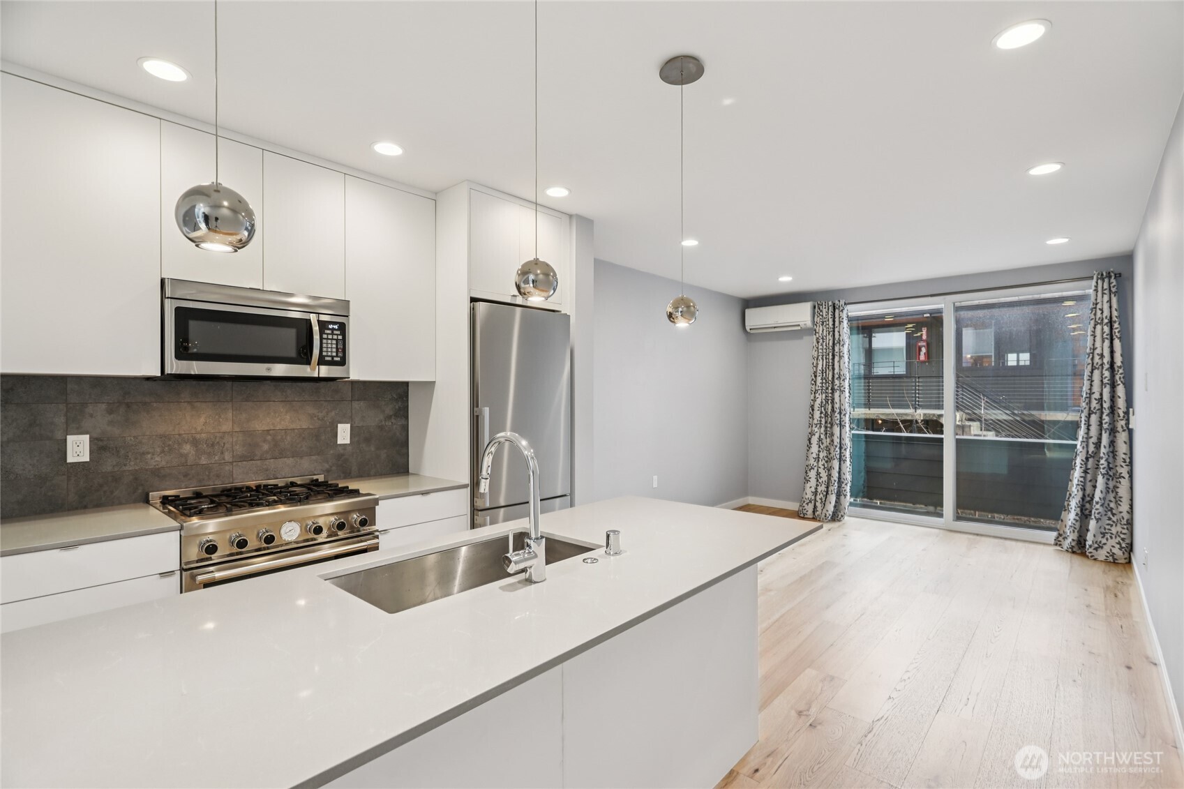 1117 Northwest 56th Street, Unit D Seattle, WA 98107 - Photo 6 of 32 a kitchen with stainless steel appliances a stove a refrigerator a microwave and island