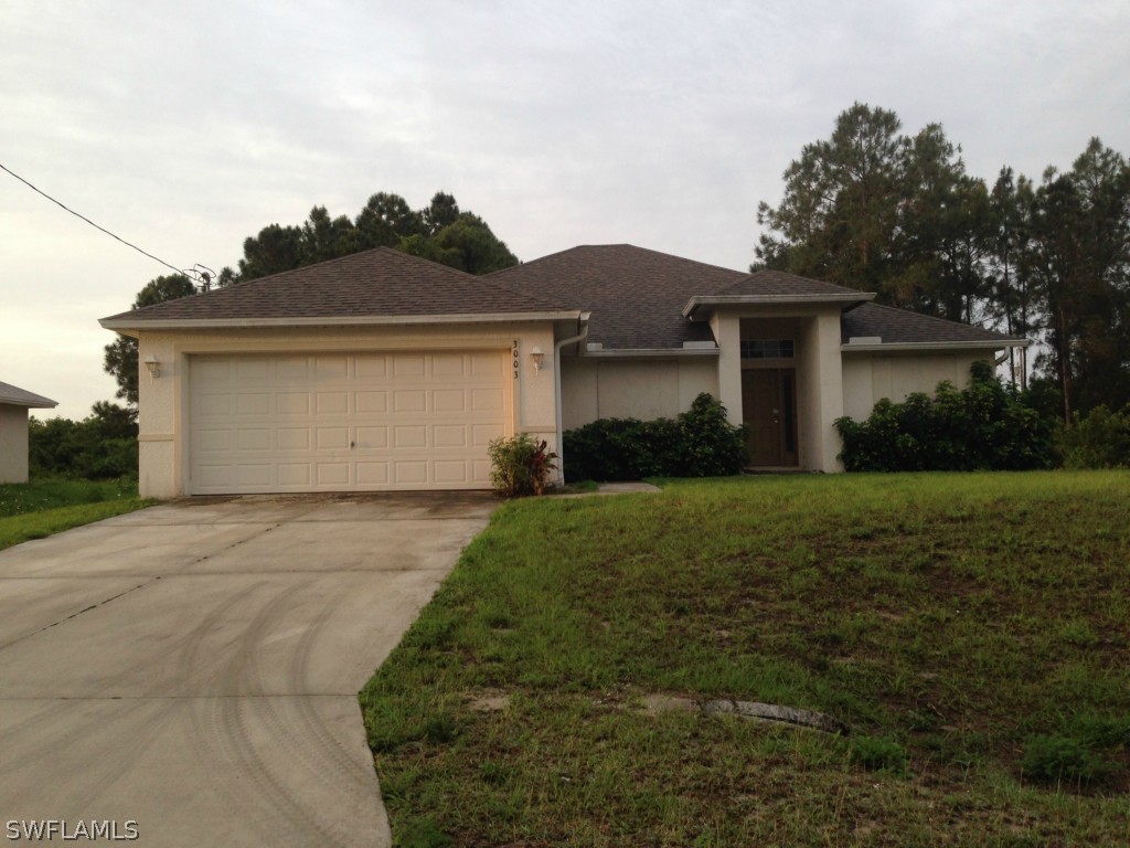 3003 37th Street Southwest Lehigh Acres, FL 33976 - Photo 1 of 13 a front view of a house with a yard and garage