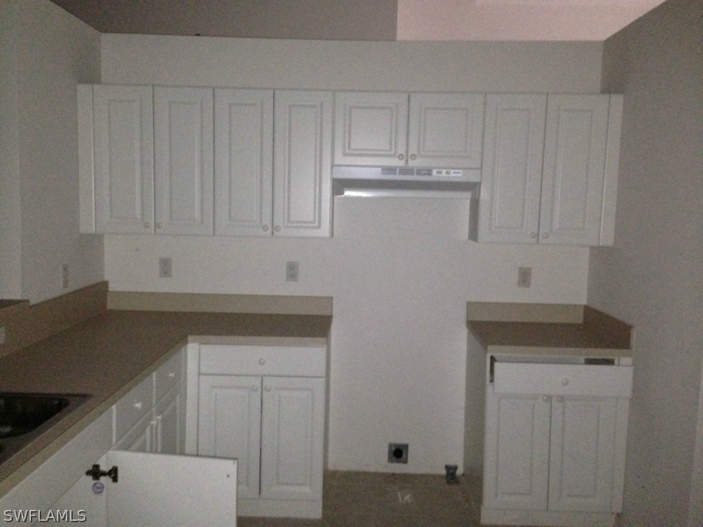 3003 37th Street Southwest Lehigh Acres, FL 33976 - Photo 6 of 13 a kitchen with white cabinets and sink