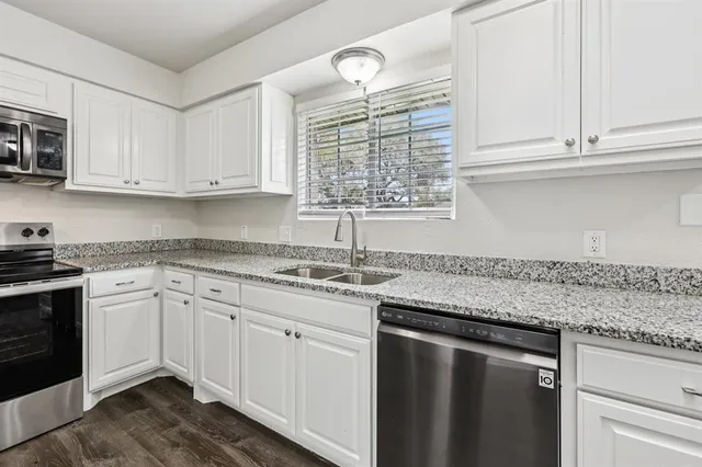 a kitchen with granite countertop white cabinets and white appliances