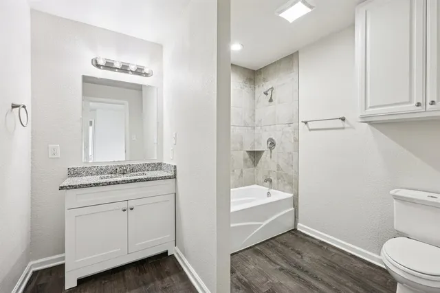 a bathroom with a granite countertop sink a toilet and shower