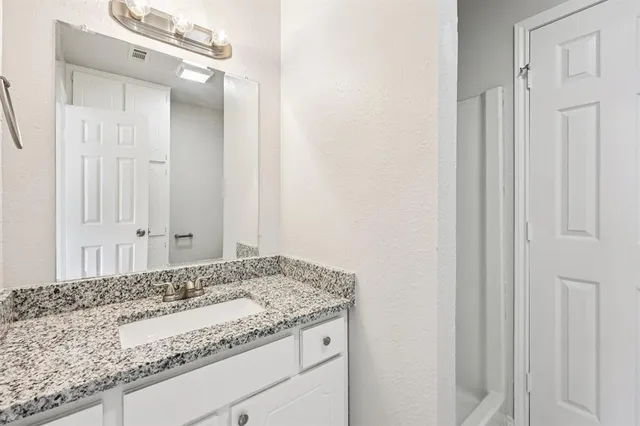 a bathroom with a granite countertop sink and a mirror