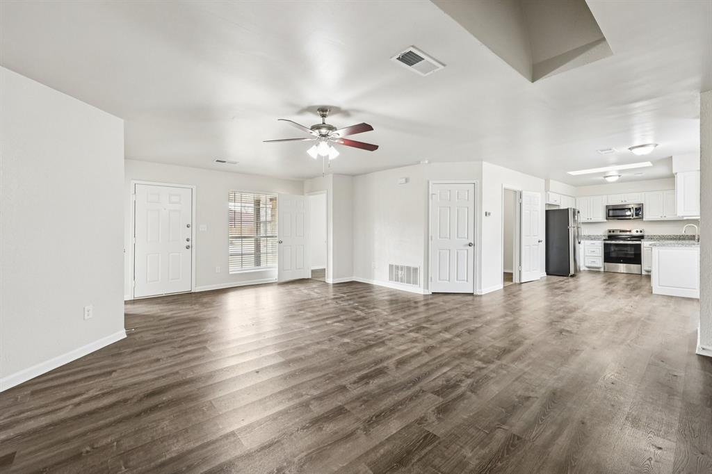 320 Edgewood Street Krum, TX 76249 - Photo 6 of 29 a view of an empty room with wooden floor and a ceiling fan