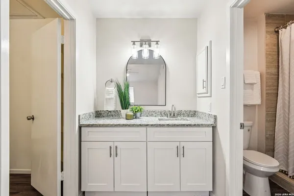 a bathroom with a granite countertop toilet sink and mirror