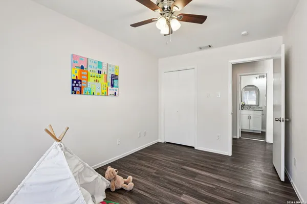 a view of a bedroom with wooden floor and ceiling fan